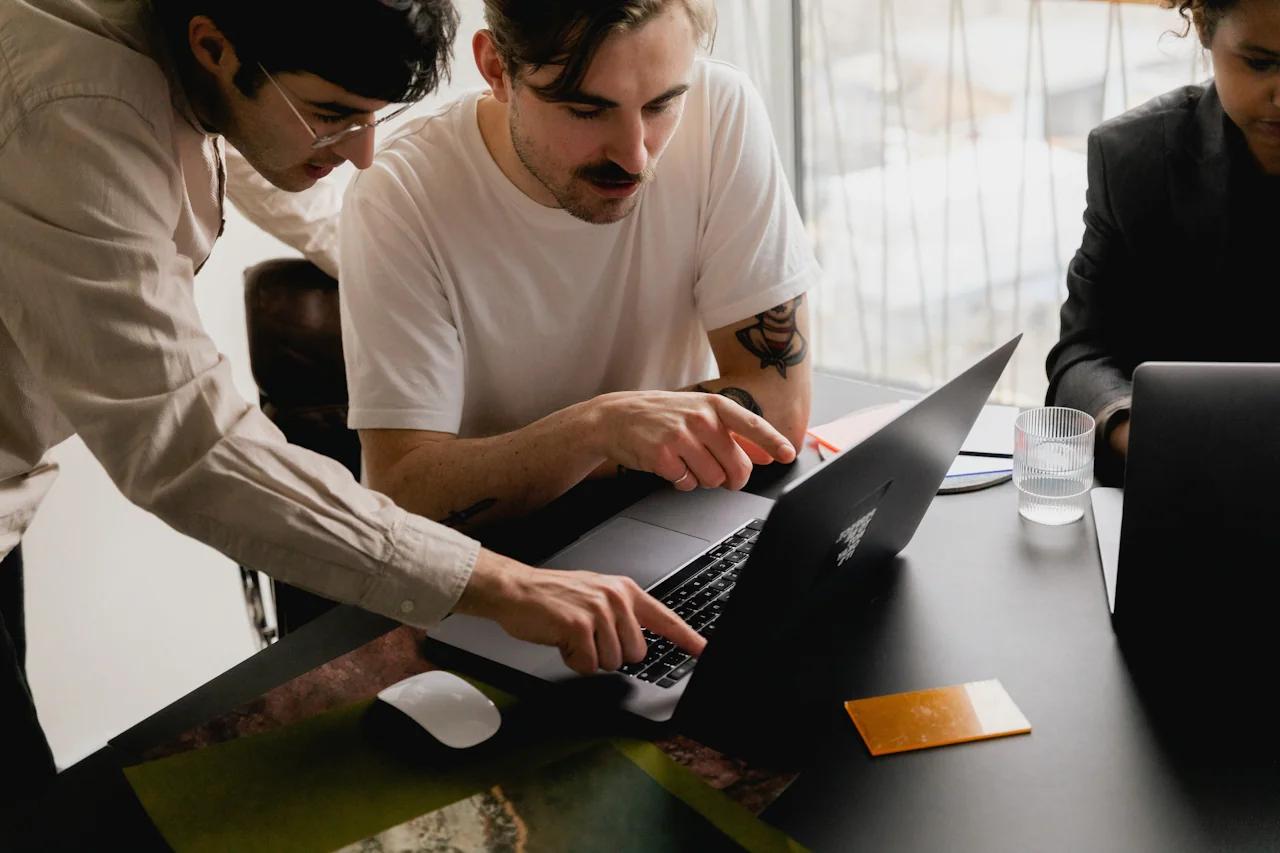 Two men working together on a laptop.