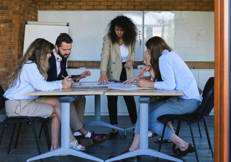 Group of five people having a meeting around a table.