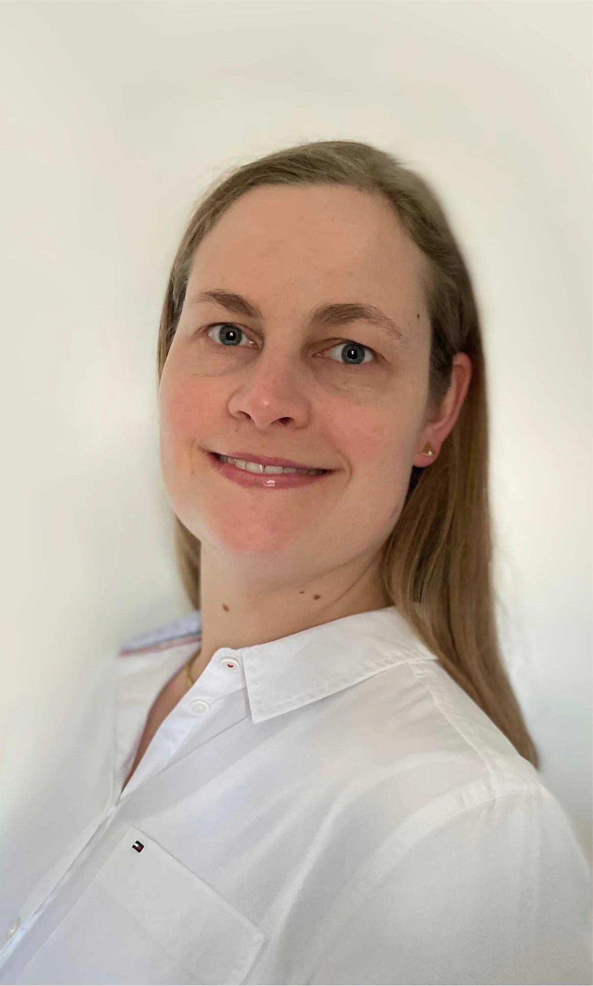 Portrait of a smiling woman in white shirt against white background.
