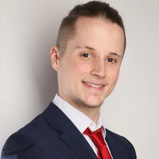 Porträtfoto eines lächelnden Mannes im Anzug und roter Krawatte