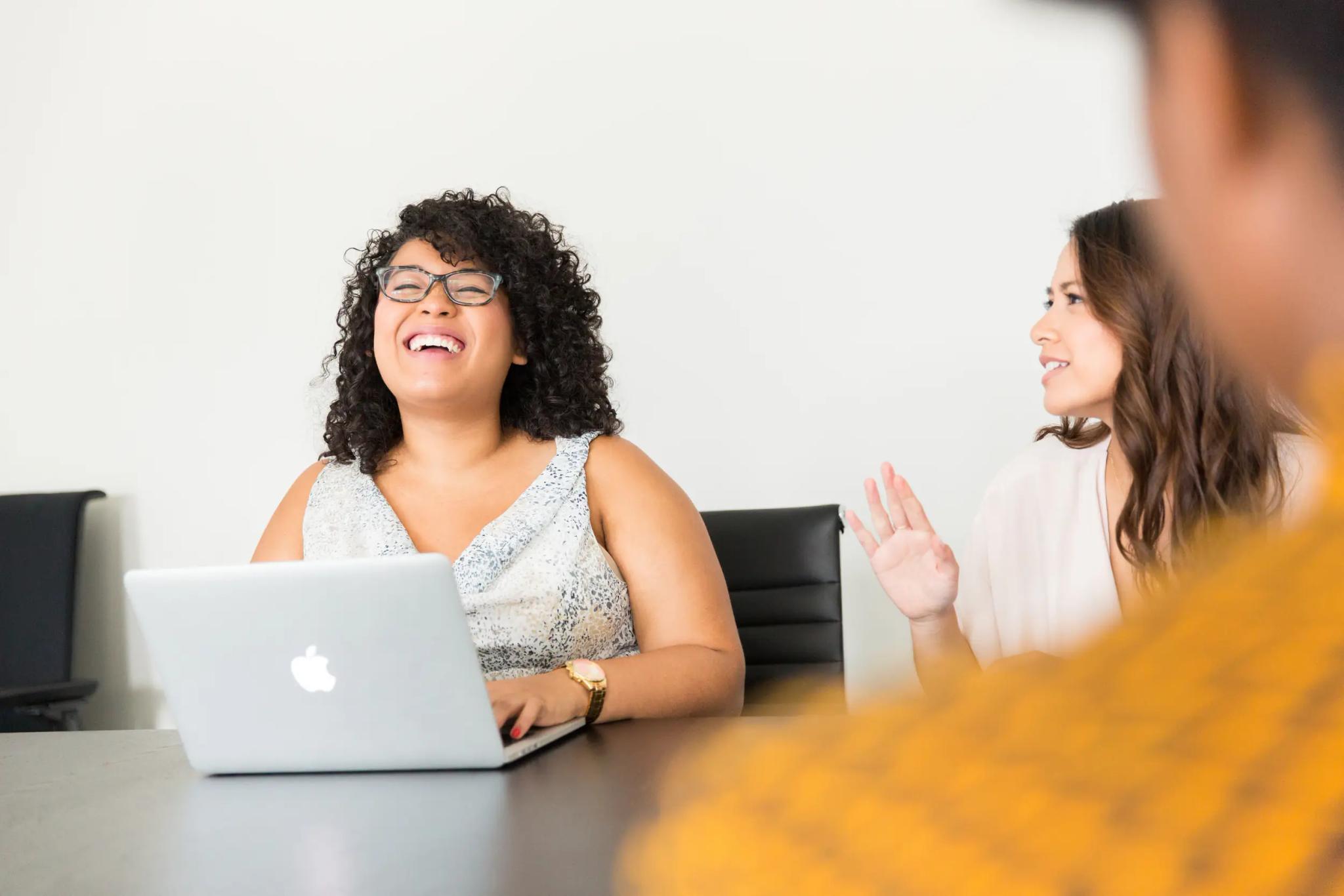 Smiling woman with laptop in a meeting.
