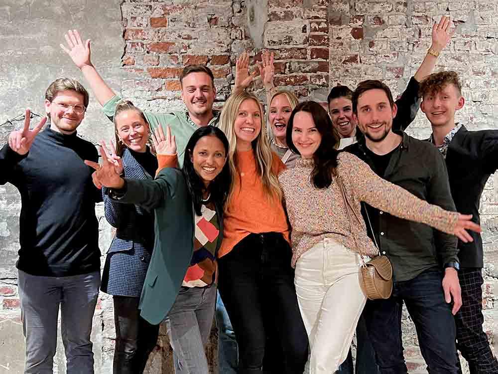 Group of ten happy people in front of a brick wall