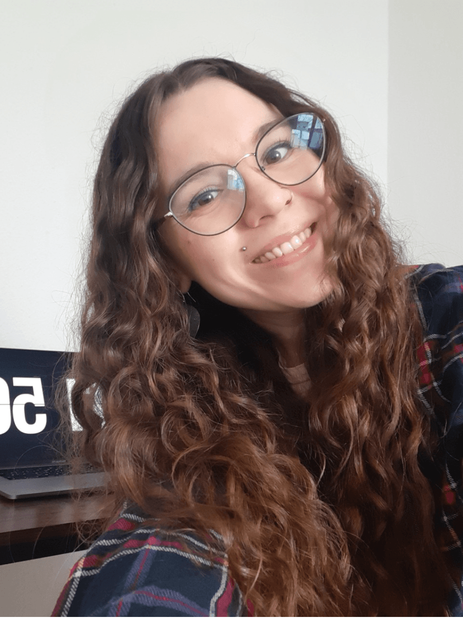 Fröhliche Frau mit Brille und lockigem Haar macht ein Selfie.