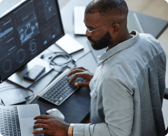 Mann arbeitet am Computer mit mehreren Bildschirmen.