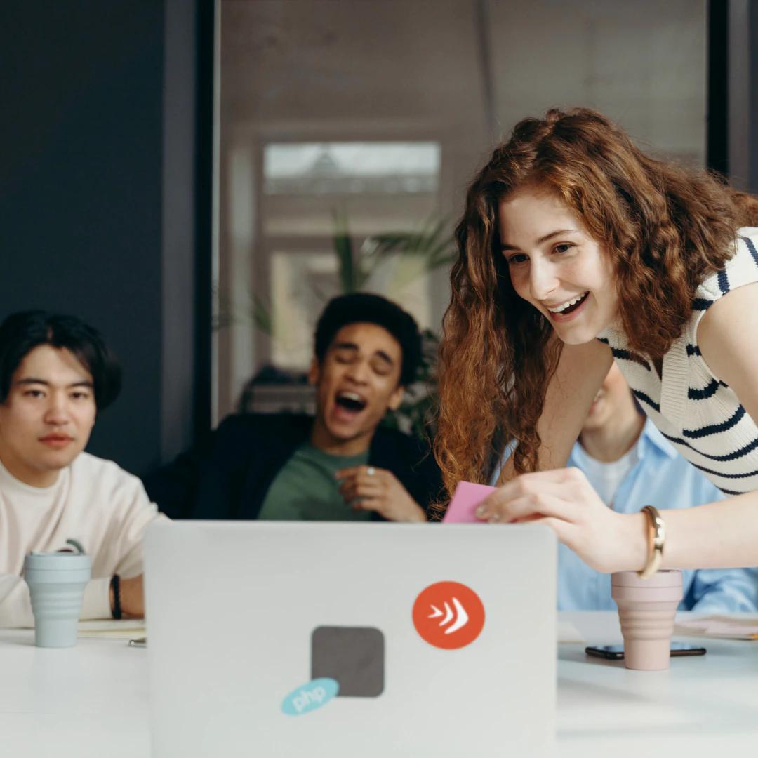 Gruppe junger Menschen, die vor einem Laptop lachen und Spaß haben.