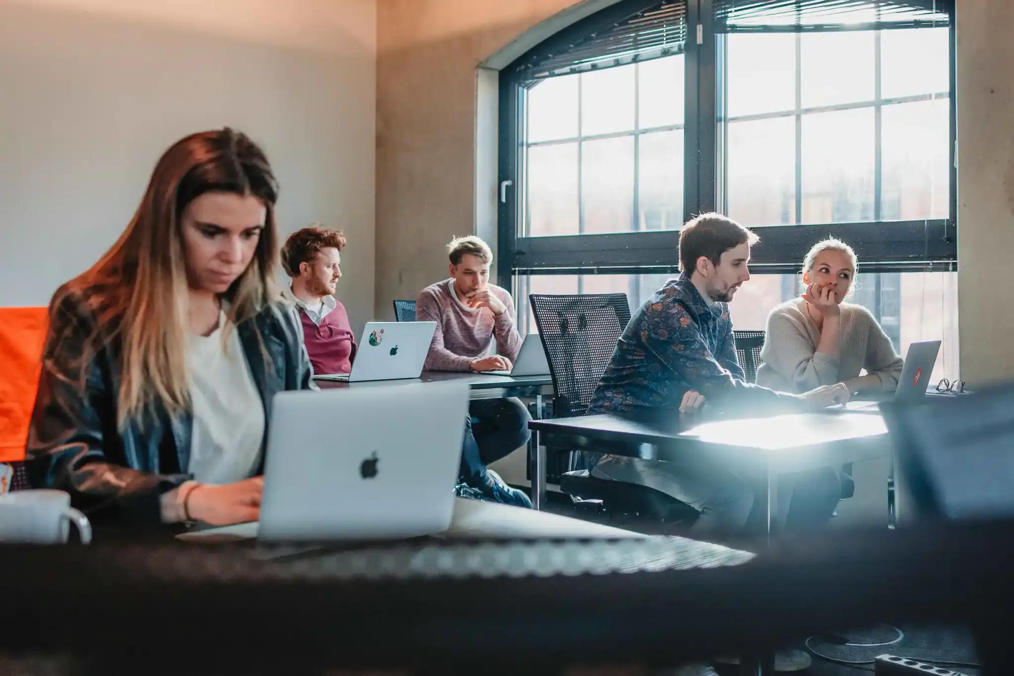 Menschen in einem modernen Arbeitsumfeld mit Laptops.