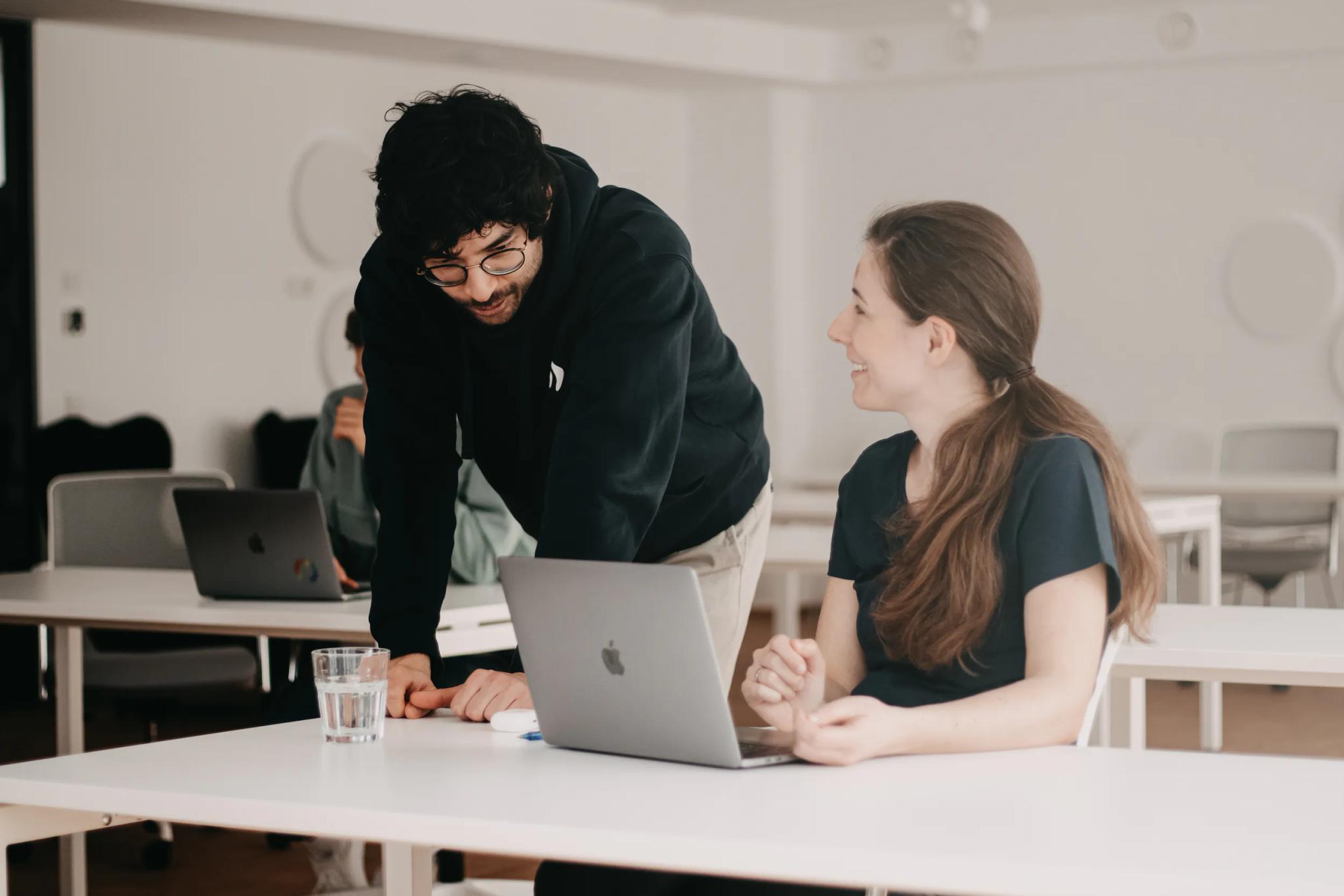 Kollegen arbeiten zusammen am Laptop in einem Büro.