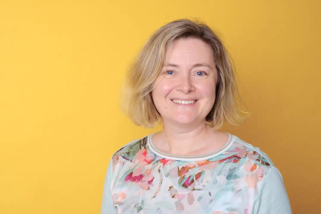 Porträt einer lächelnden Frau vor gelbem Hintergrund