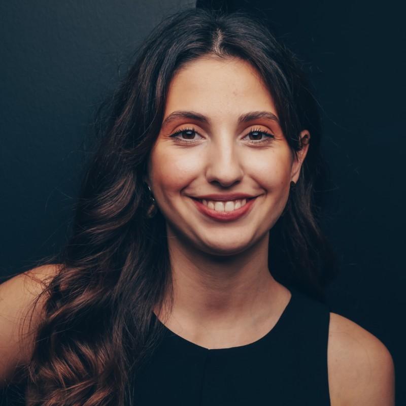 Porträt einer lächelnden Frau vor dunklem Hintergrund