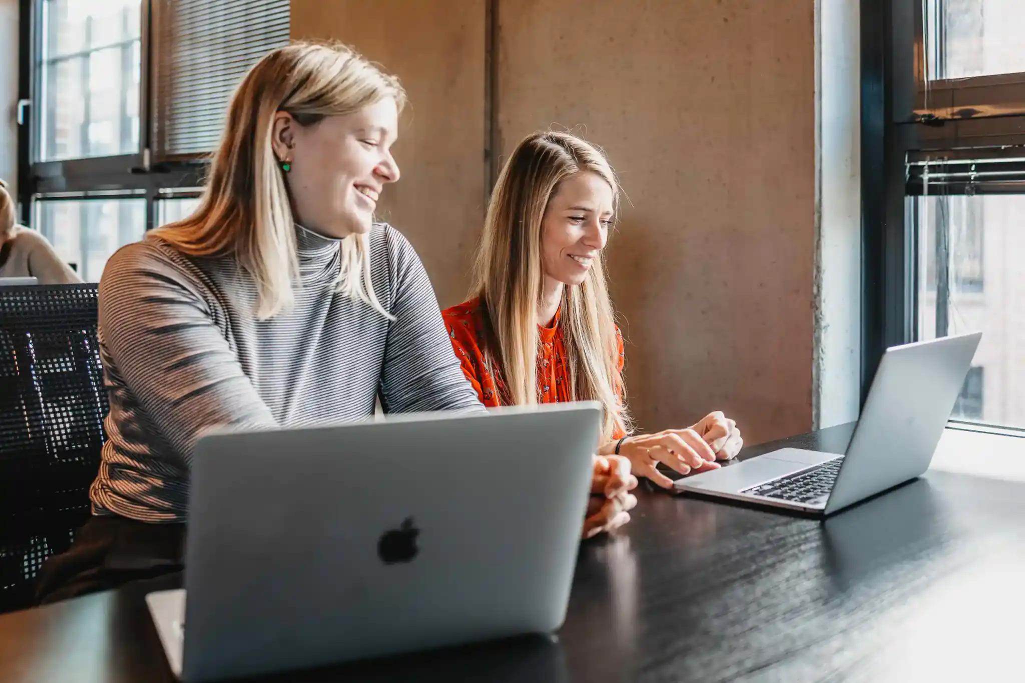Zwei Frauen arbeiten zusammen an Laptops
