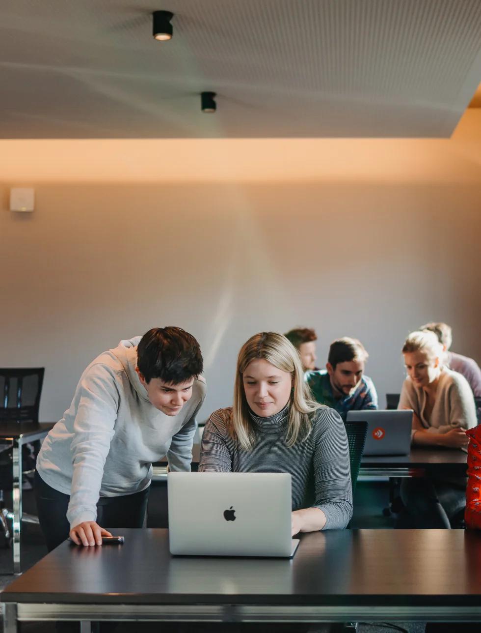 Menschen arbeiten gemeinsam an Laptops in einem modernen Büro.