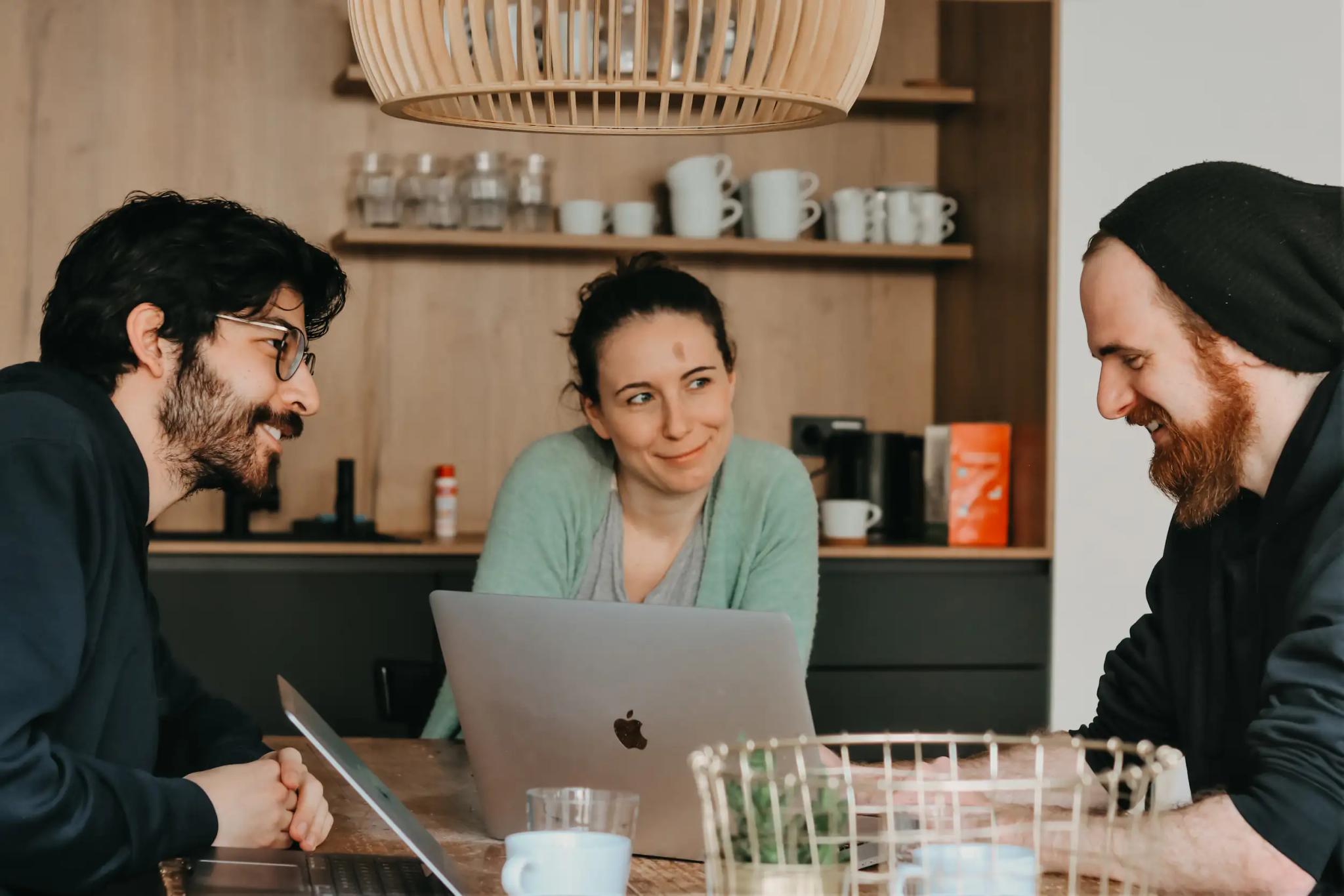Drei Personen unterhalten sich bei einem Treffen mit Laptops