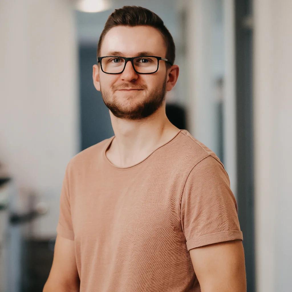 Portrait of a young man wearing glasses and a beige t-shirt