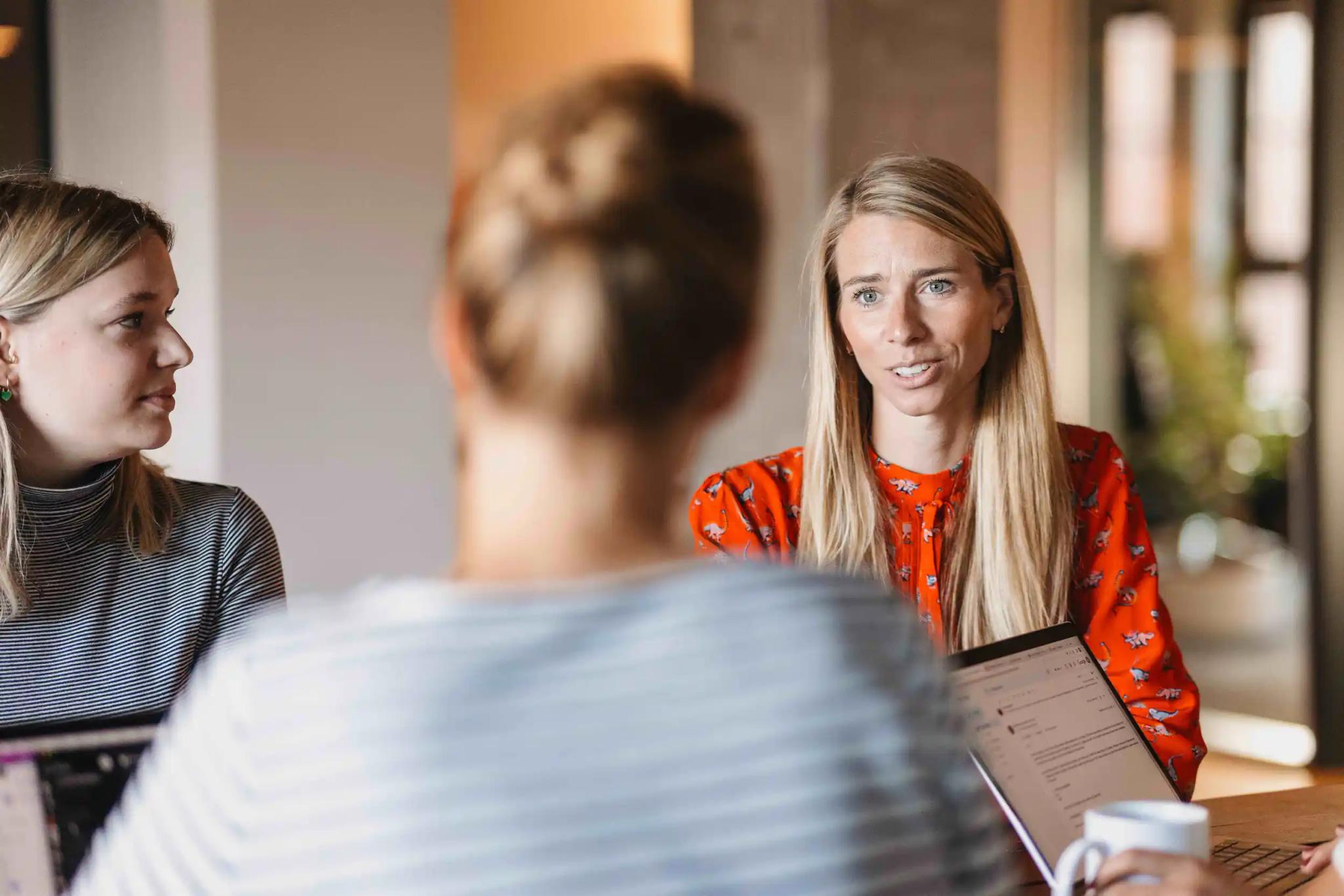 Three women talking during a meeting.