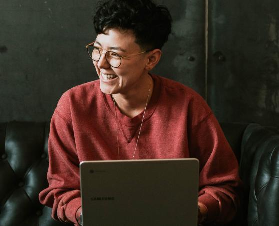 Person lacht mit Laptop auf dem Schoß