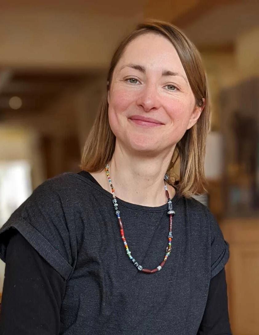 Lächelnde Frau mit Halskette in einem Innenraum.