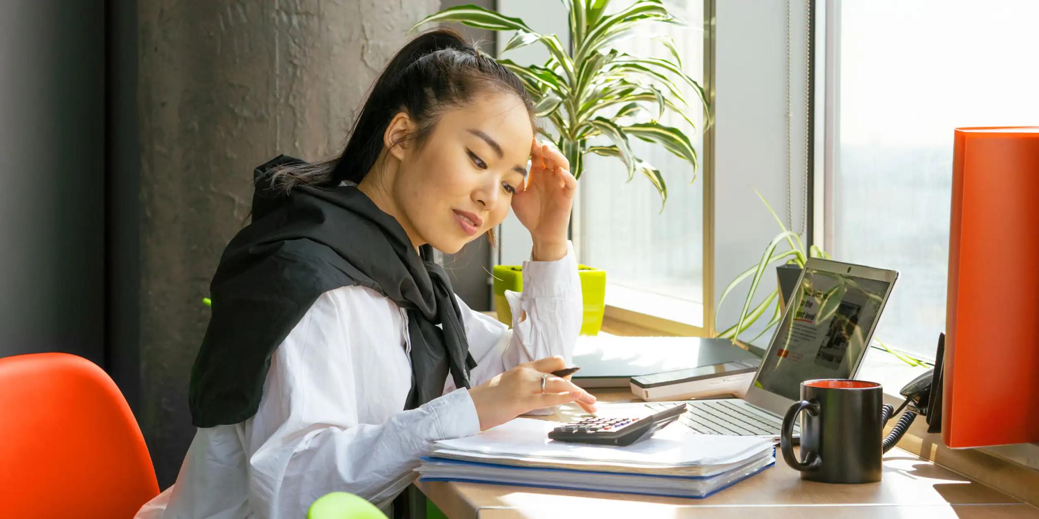 Woman working on laptop and using calculator
