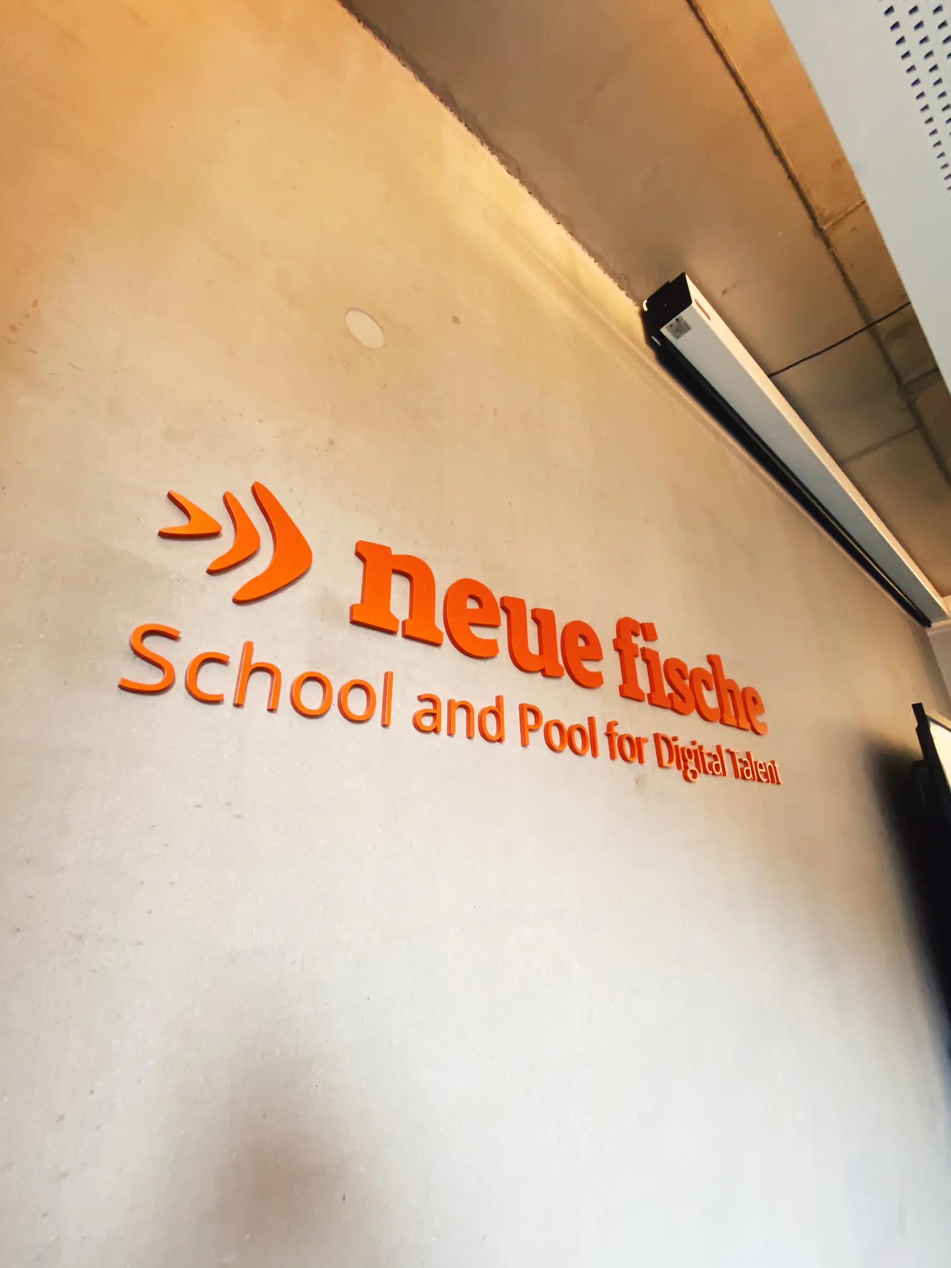 Logo and lettering of 'neue fische' on a wall.