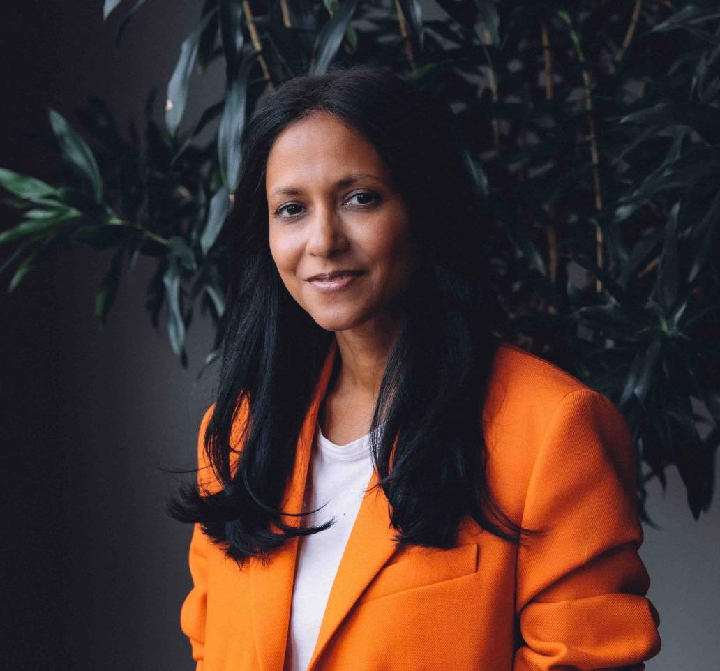 Frau in oranger Jacke vor Pflanzen