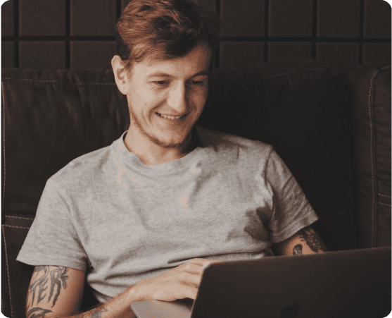 Mann lächelt, während er einen Laptop benutzt