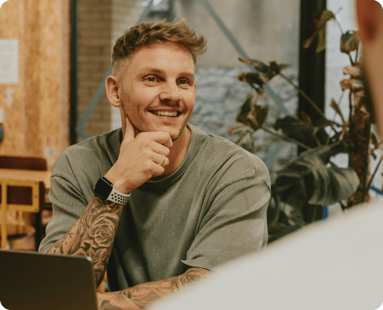 Lächelnder Mann mit Tattoo, der sich in einem Gespräch befindet