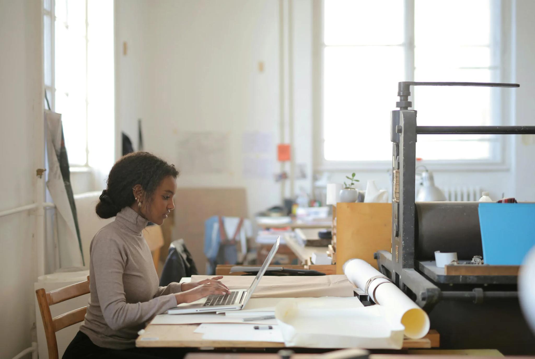 Frau arbeitet am Laptop in einem Atelier.