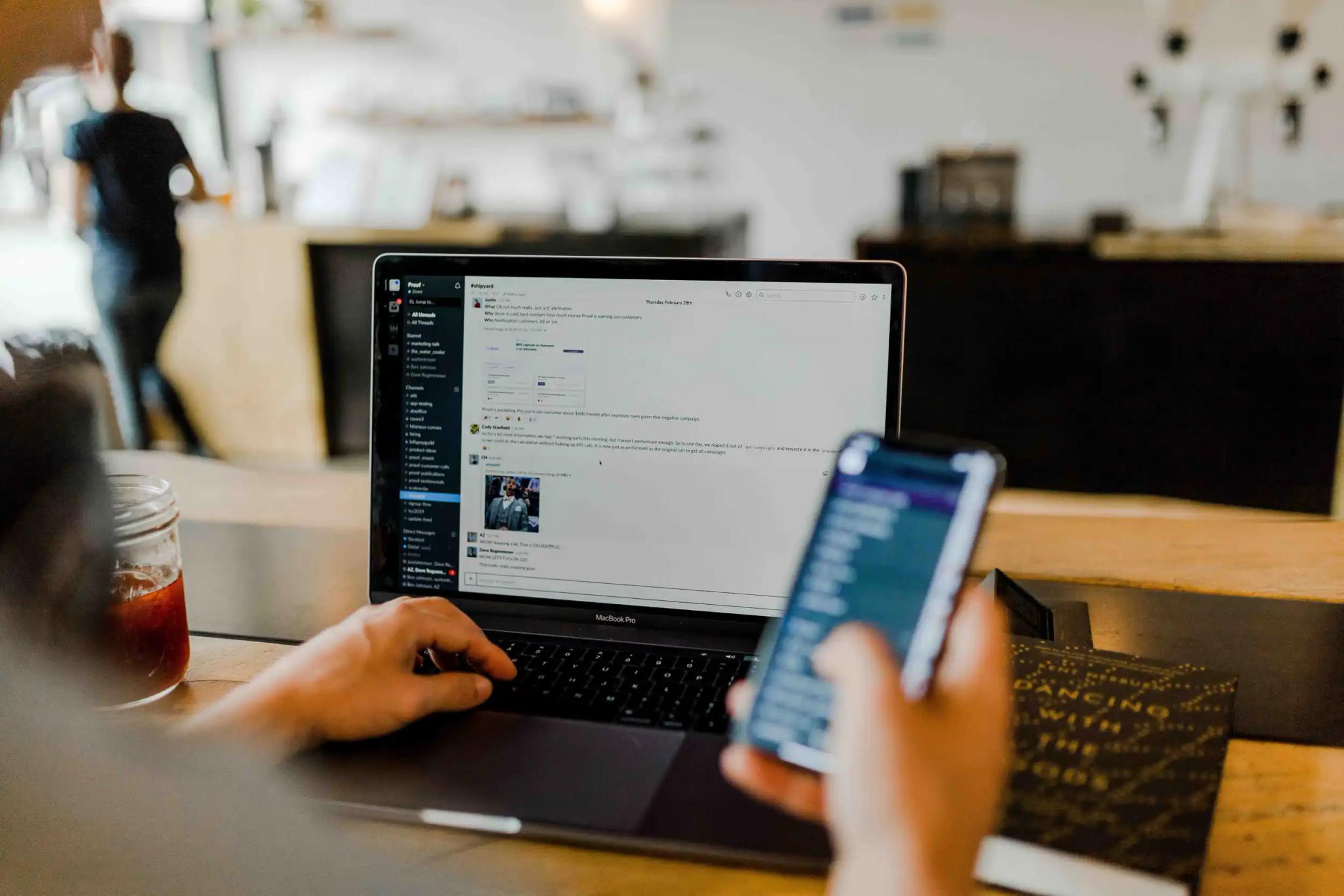 Person working on a laptop and smartphone in a café.