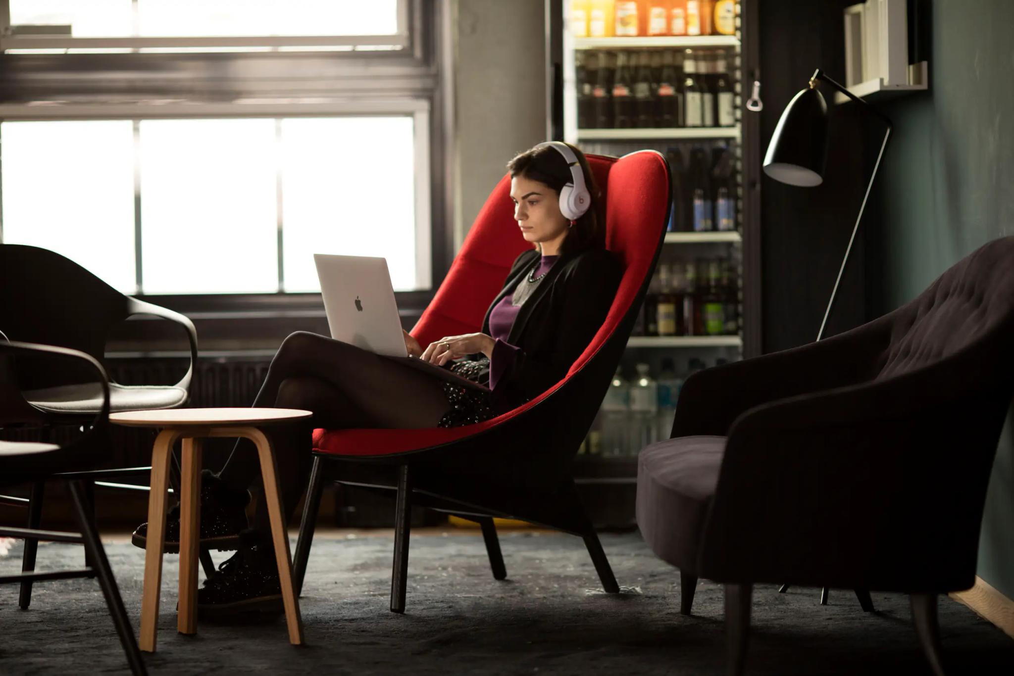 Woman with headphones working on laptop in modern living room.