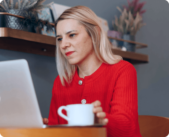 Frau arbeitet am Laptop mit Kaffeetasse