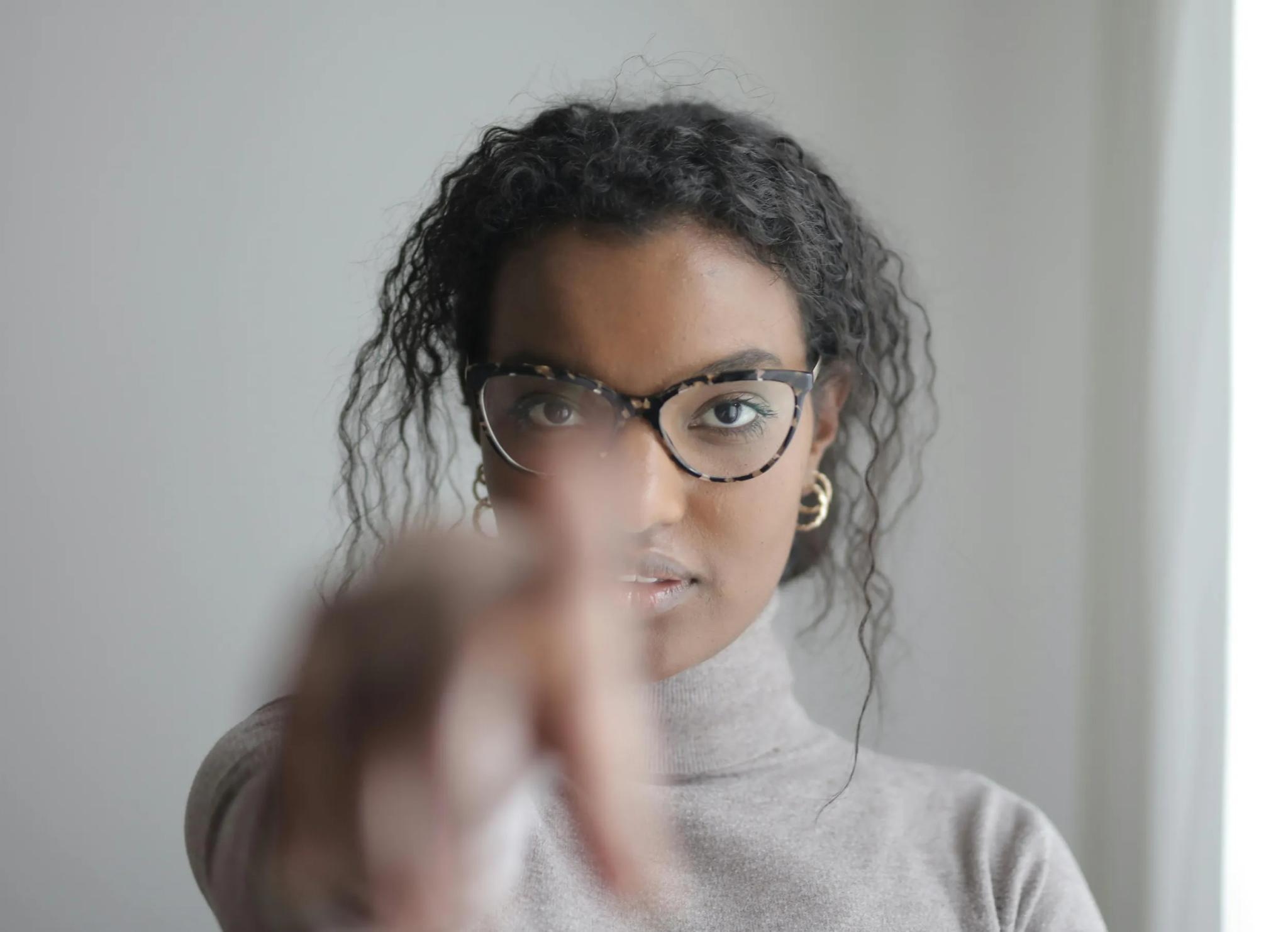Woman wearing glasses pointing at the camera