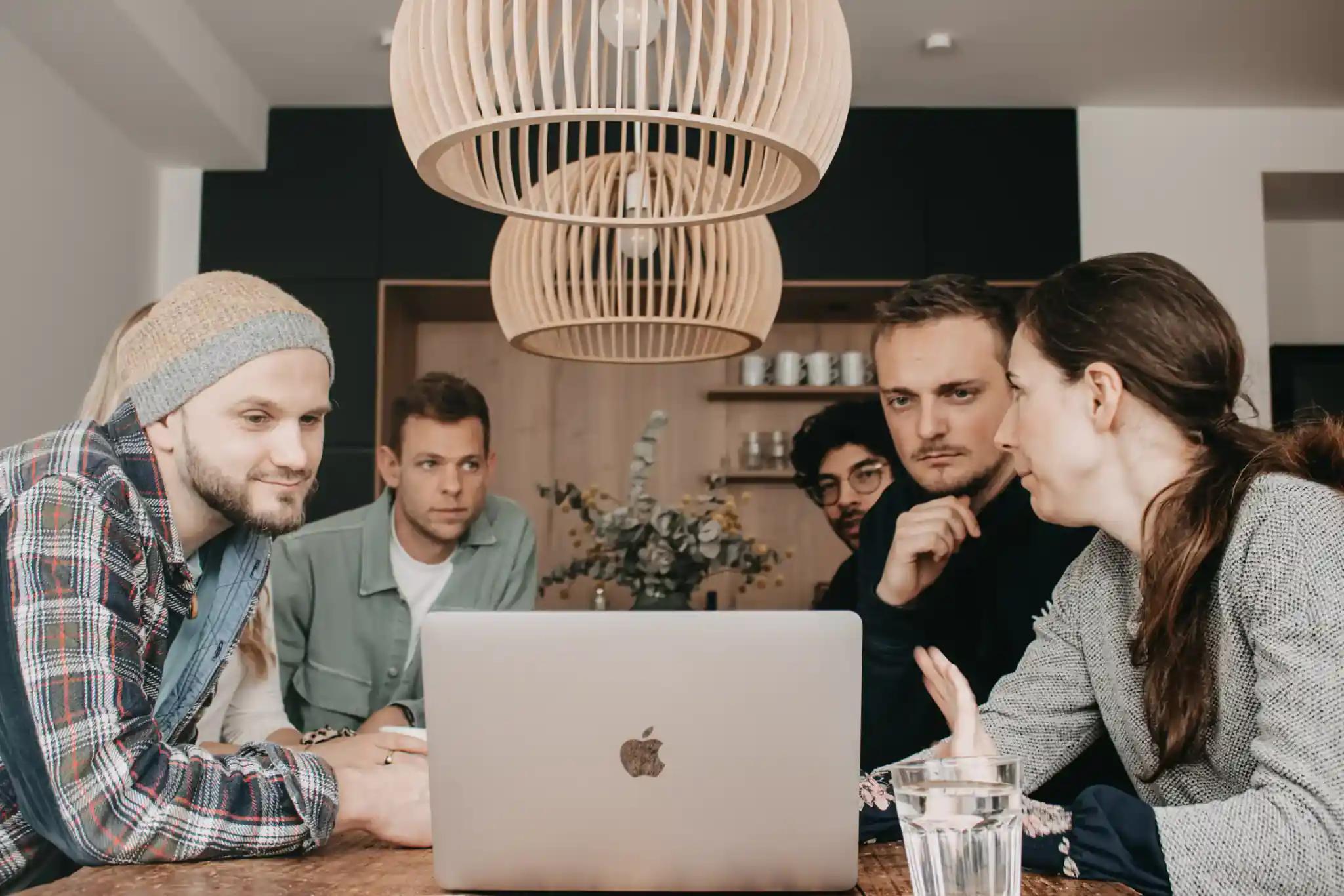 Gruppe von Menschen, die an einem Tisch mit Laptop arbeitet