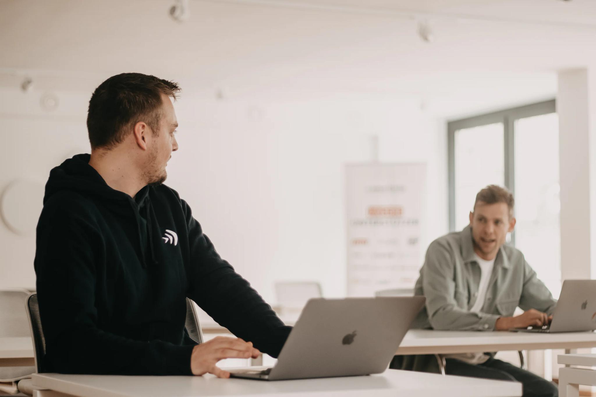 Zwei Männer arbeiten mit Laptops in einem modernen Büro.