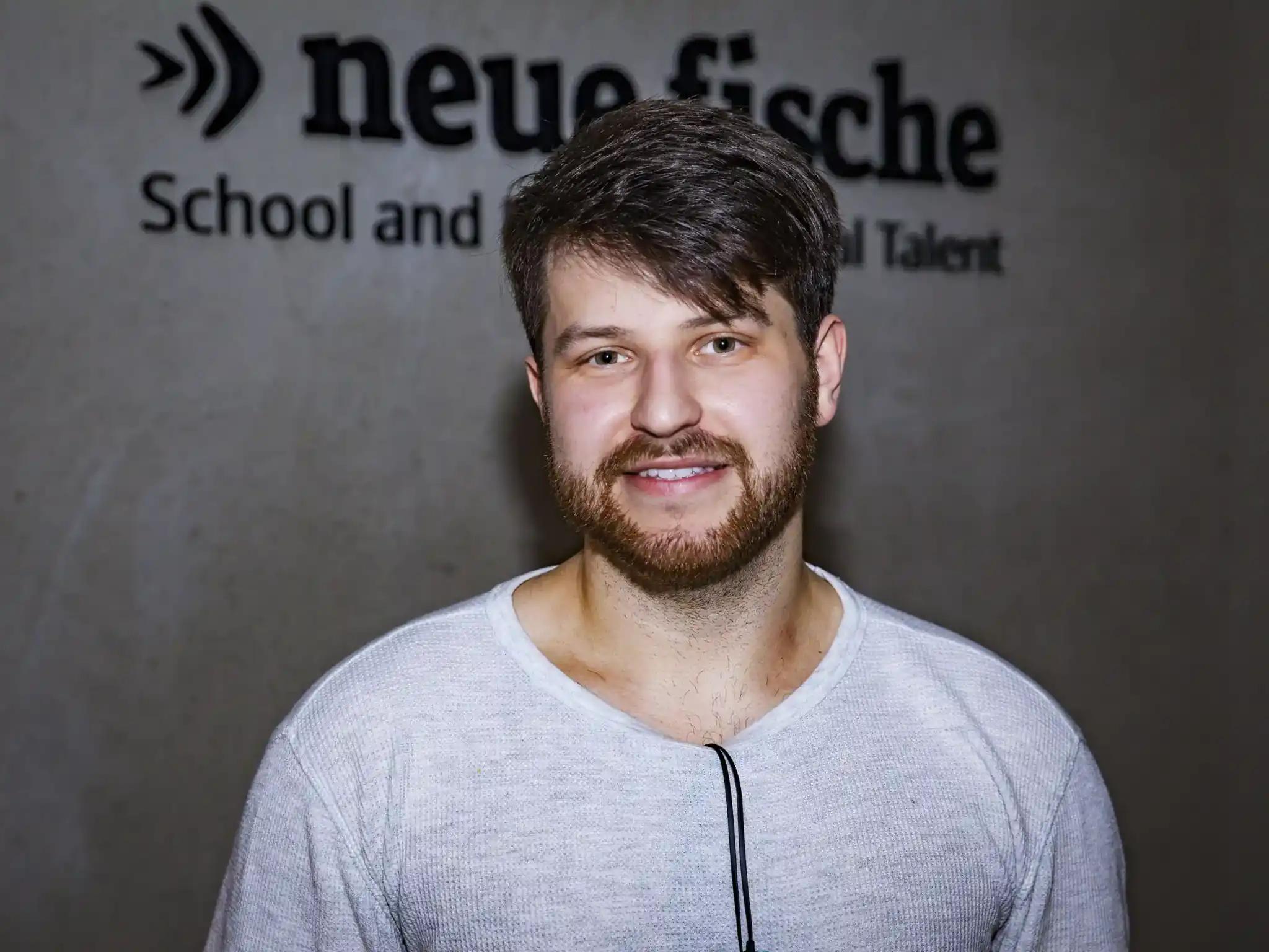 Smiling young man in front of a wall with text.