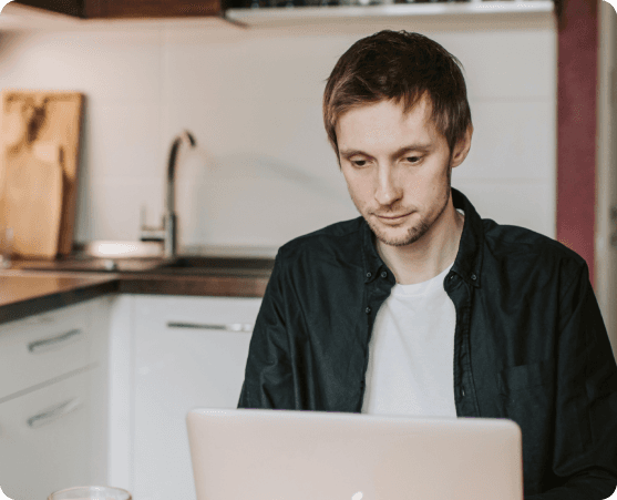 Mann arbeitet am Laptop in der Küche