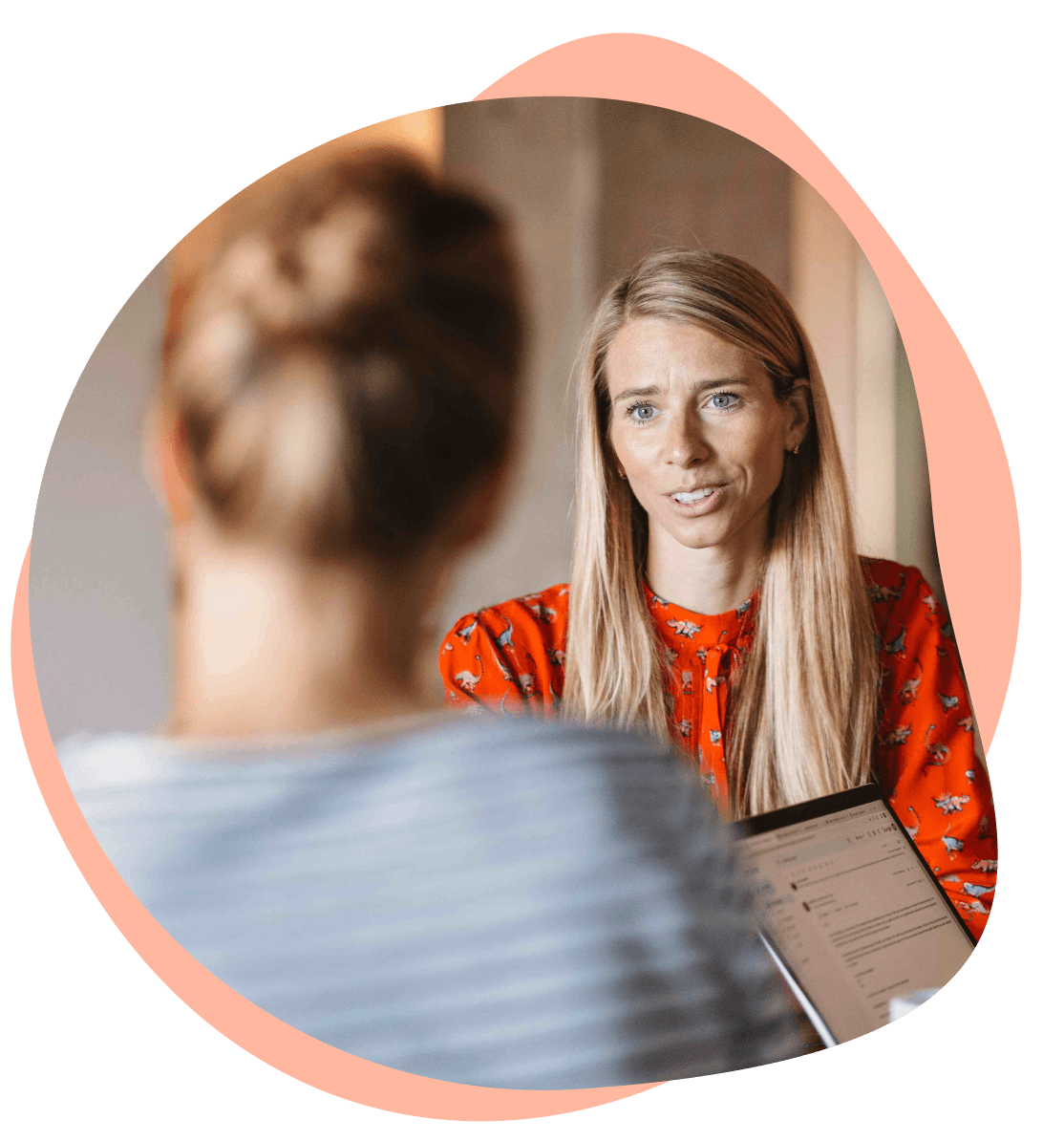 Zwei Frauen im Gespräch, eine mit Laptop