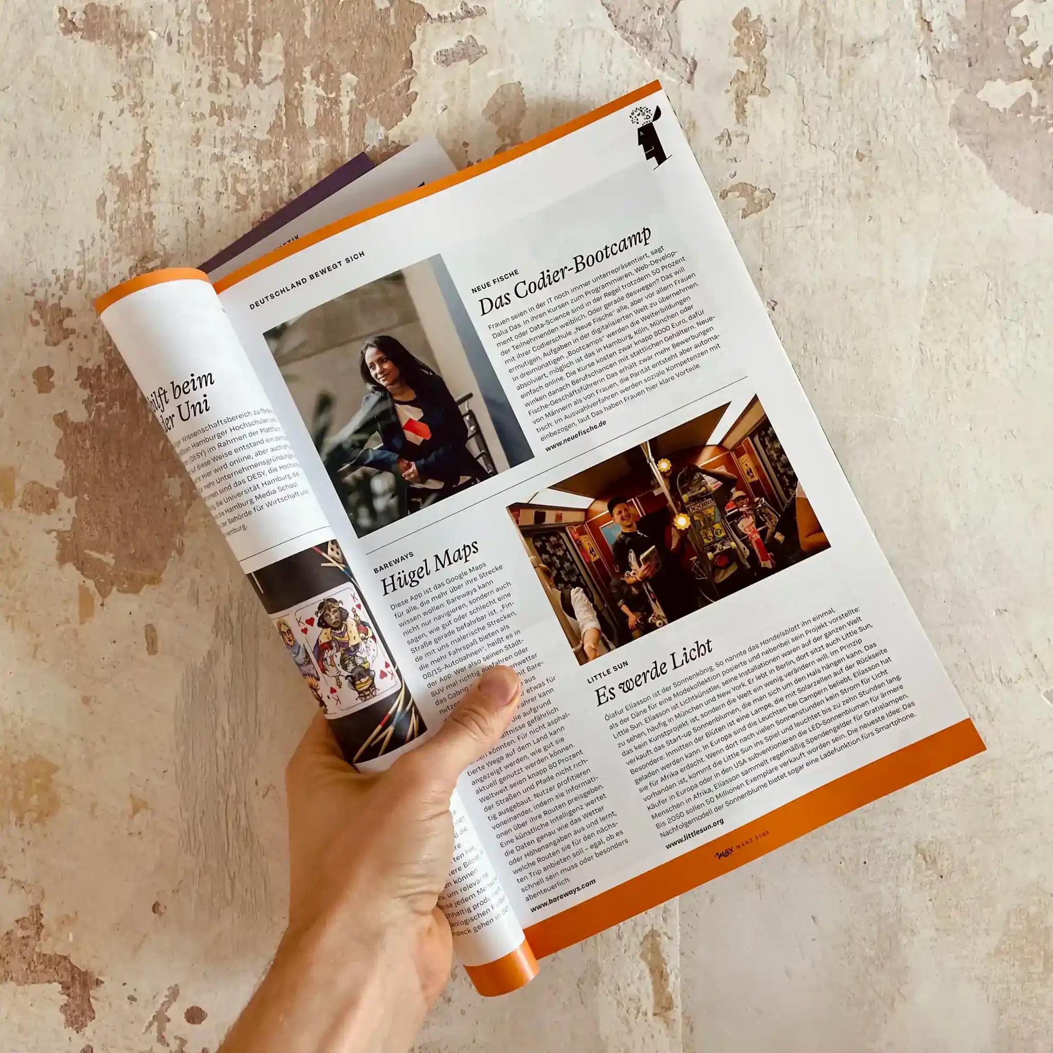 Hand holding an open magazine with pictures and text.