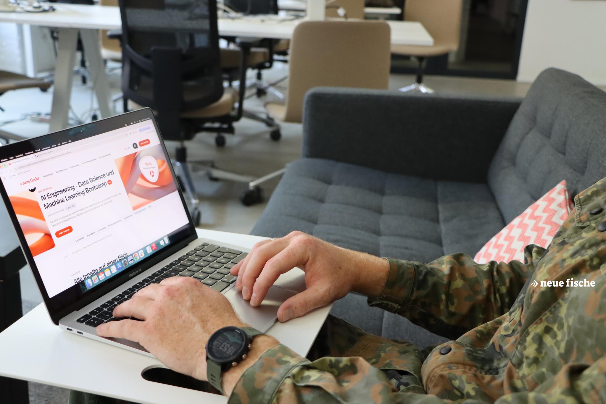 Person in Tarnuniform arbeitet an Laptop in Büro