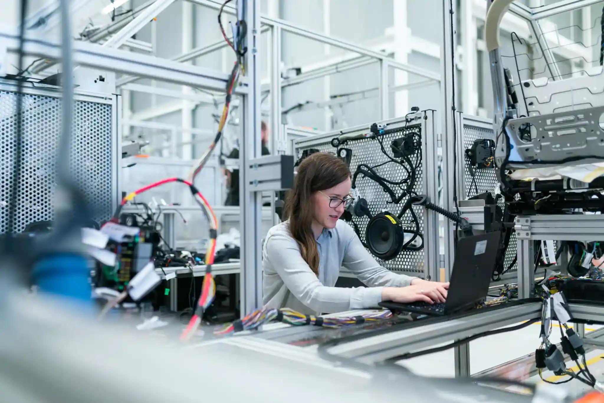 Woman working on a laptop in a modern factory.